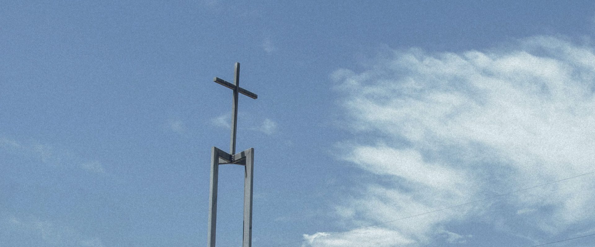 the iconic Waurn Ponds Community Church metal cross agains a cloudy blue sky